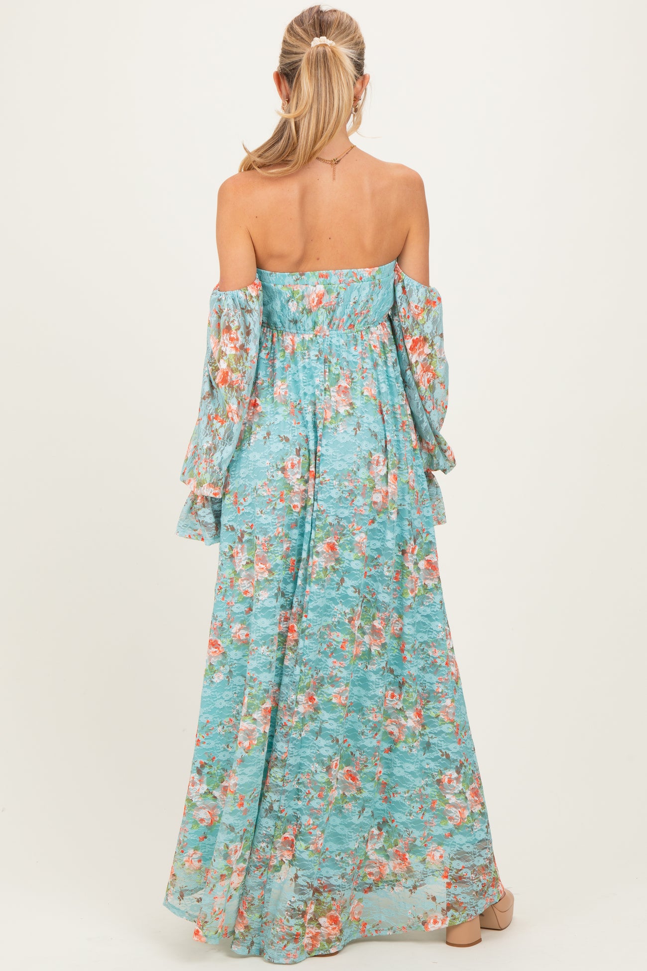 woman wearing a floral off-the-shoulder maternity maxi dress in light blue with long bell sleeves and a flowing silhouette