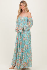 woman wearing a floral off-the-shoulder maxi dress in light blue with long sleeves and flowing design