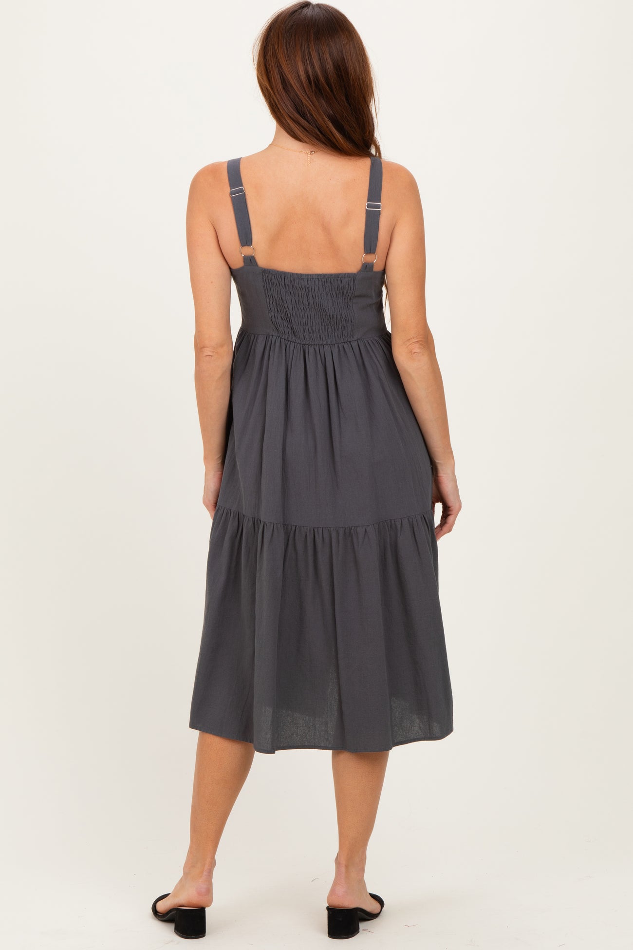 woman wearing a gray tiered midi dress with adjustable straps, showing the back view