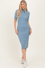 woman wearing a light blue fitted midi dress with short sleeves and a high neckline, styled with white sneakers