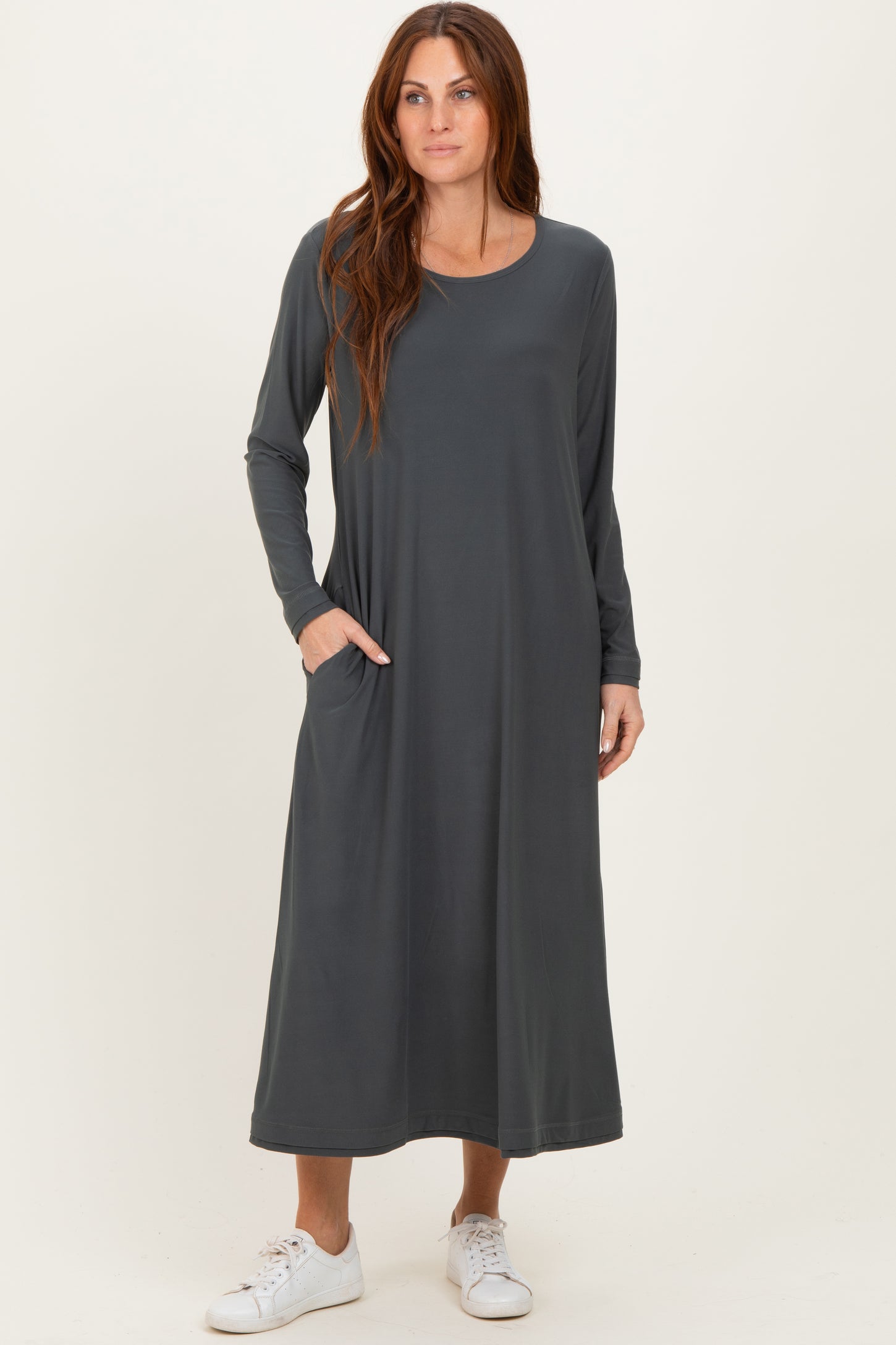 woman wearing a grey long sleeve maxi dress with pockets and white sneakers