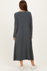 woman wearing a long sleeve dark gray maxi dress, standing with her back to the camera