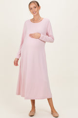 woman wearing a light pink long sleeve maternity dress and holding her baby bump