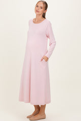 woman wearing a light pink long sleeve maternity dress with pockets and a visible baby bump