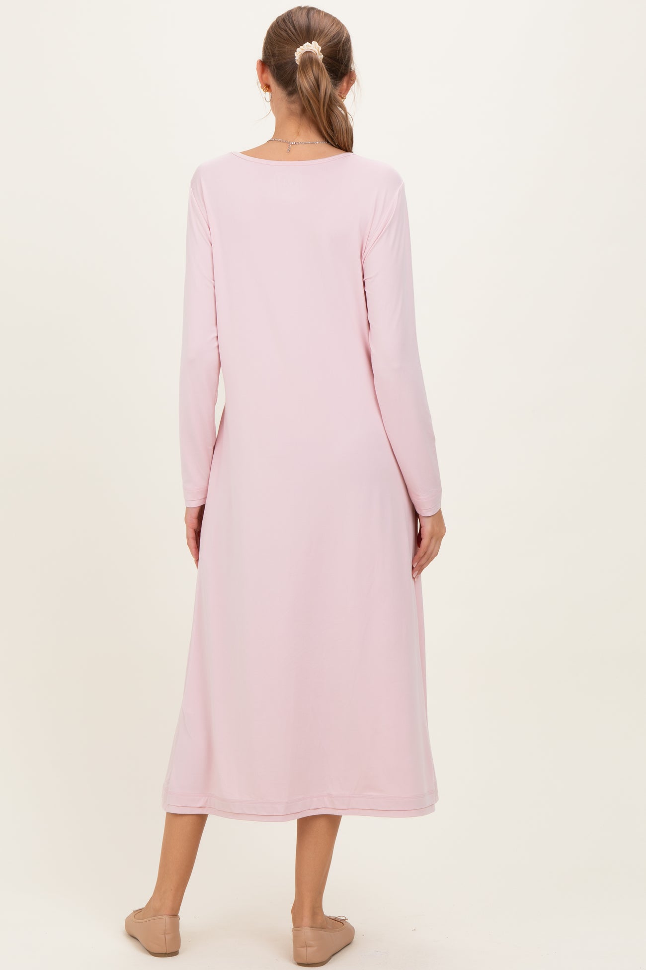 woman wearing a long sleeve pink maternity dress with a flowing silhouette, viewed from the back