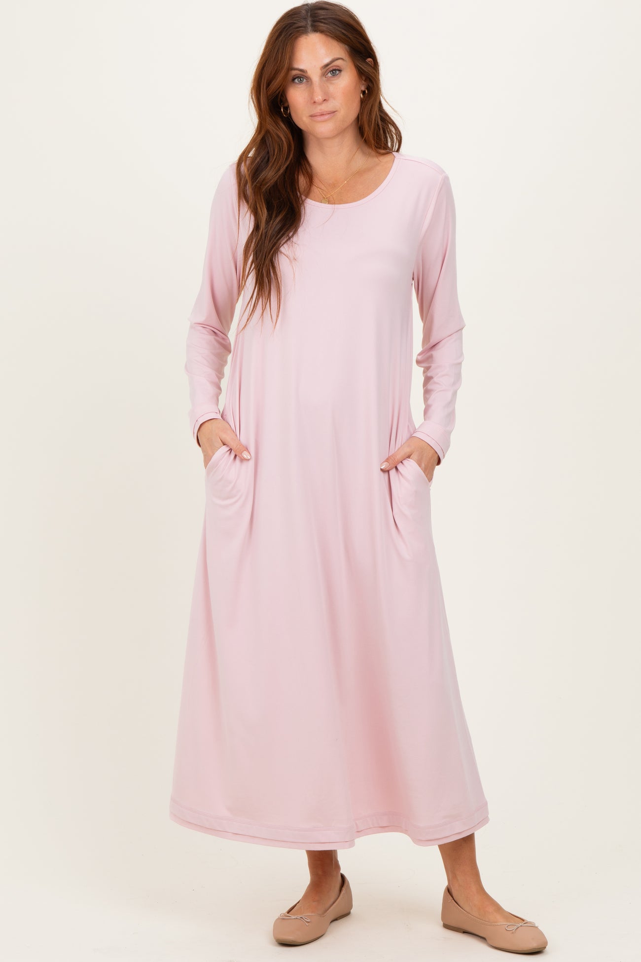 woman wearing a light pink long sleeve maxi dress with side pockets