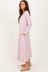 woman wearing a light pink long sleeve maxi dress with side pockets and a relaxed silhouette