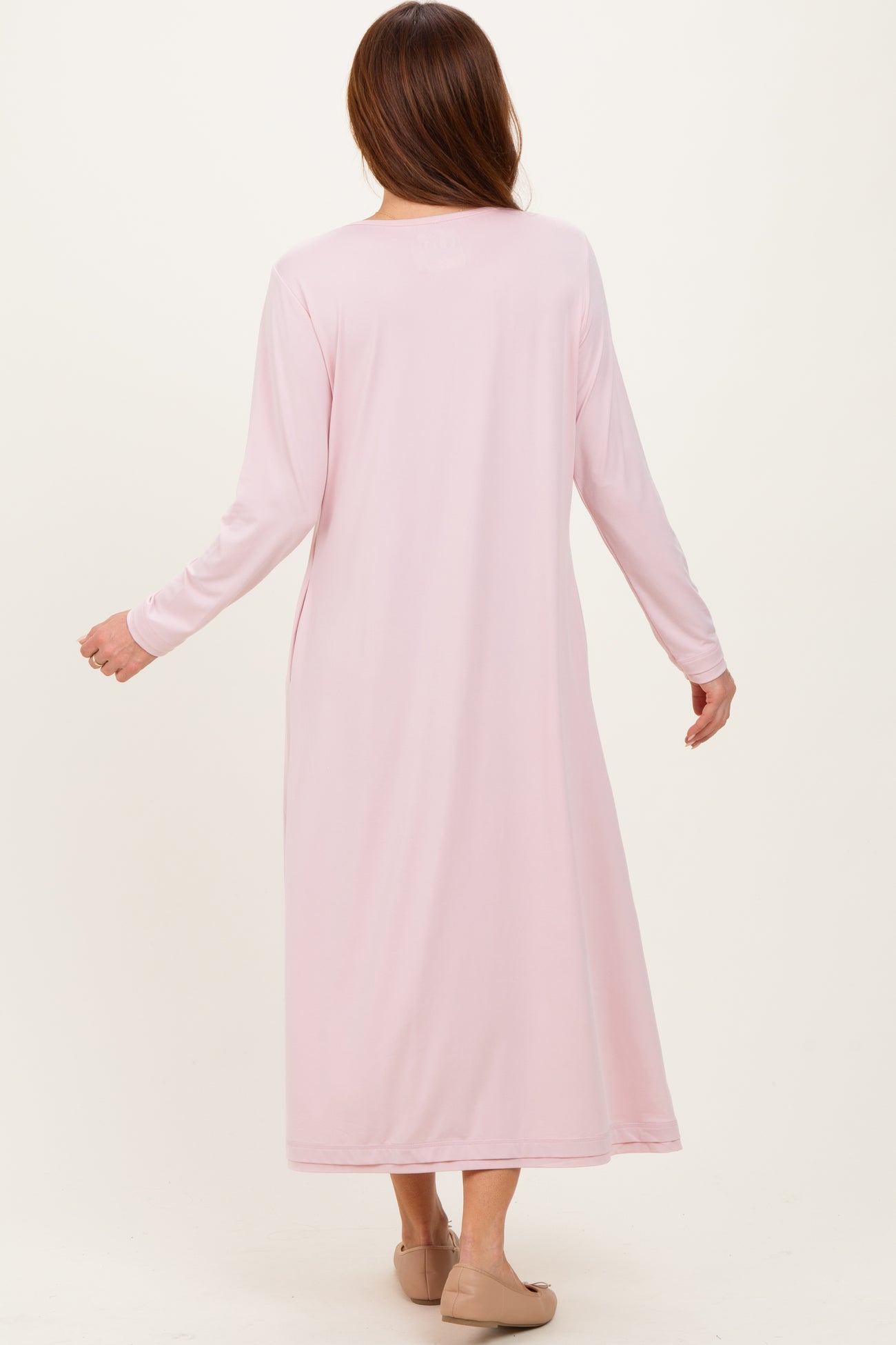 woman wearing a long pink maxi dress with long sleeves, viewed from the back