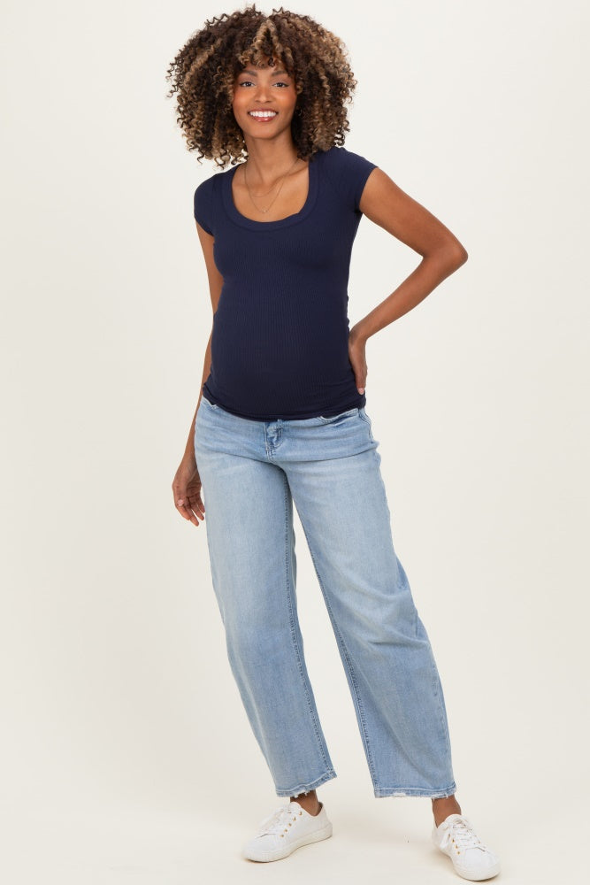woman wearing a navy blue ribbed short sleeve maternity top and light blue wide leg jeans, showing her baby bump