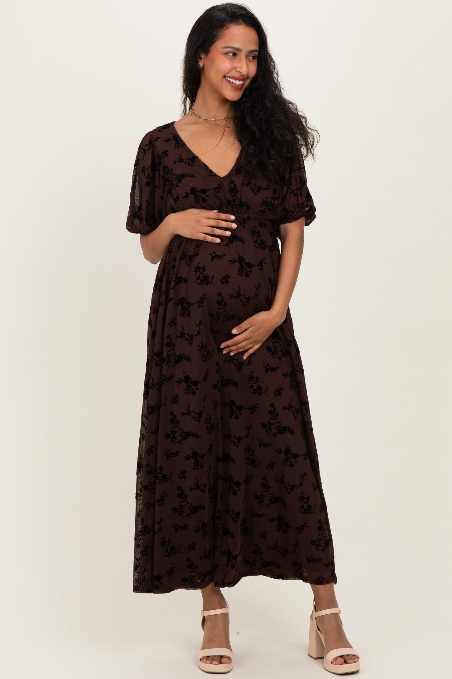 woman wearing a brown floral maternity maxi dress and holding her baby bump