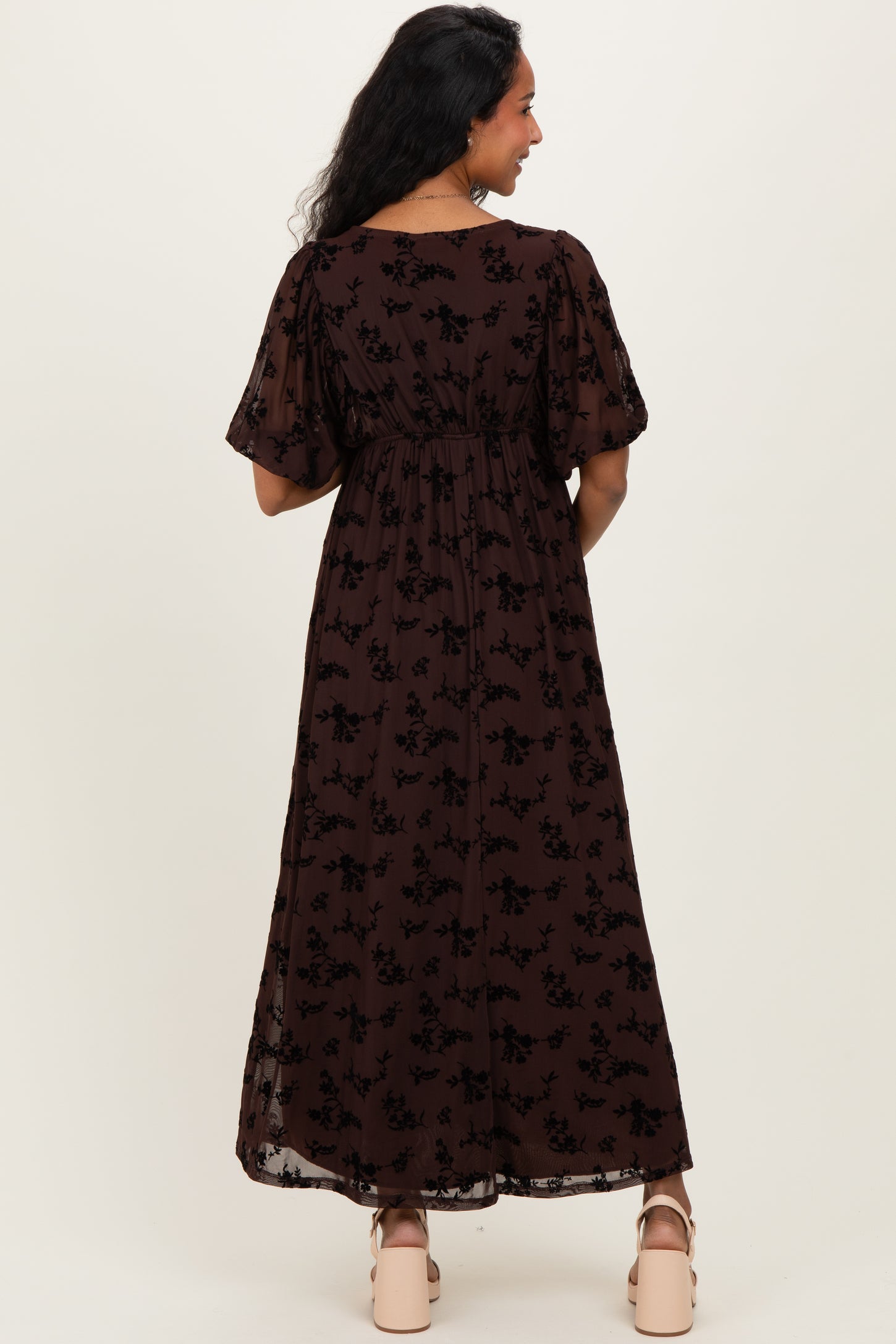woman wearing a brown floral maternity maxi dress with short sleeves and a smocked waist, showing her baby bump