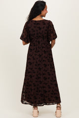 woman wearing a brown floral maternity maxi dress with short sleeves and a smocked waist, showing her baby bump
