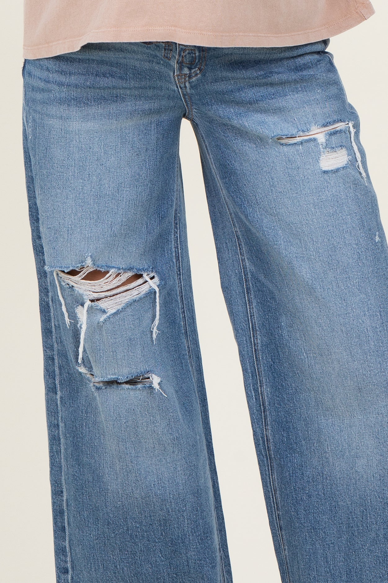woman wearing a pair of distressed maternity jeans with wide legs and ripped details
