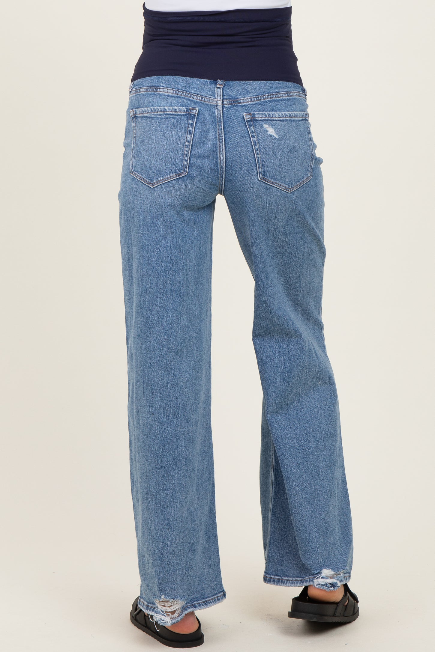 maternity wear light blue distressed wide-leg jeans with a stretchy black waistband, model facing away from the camera