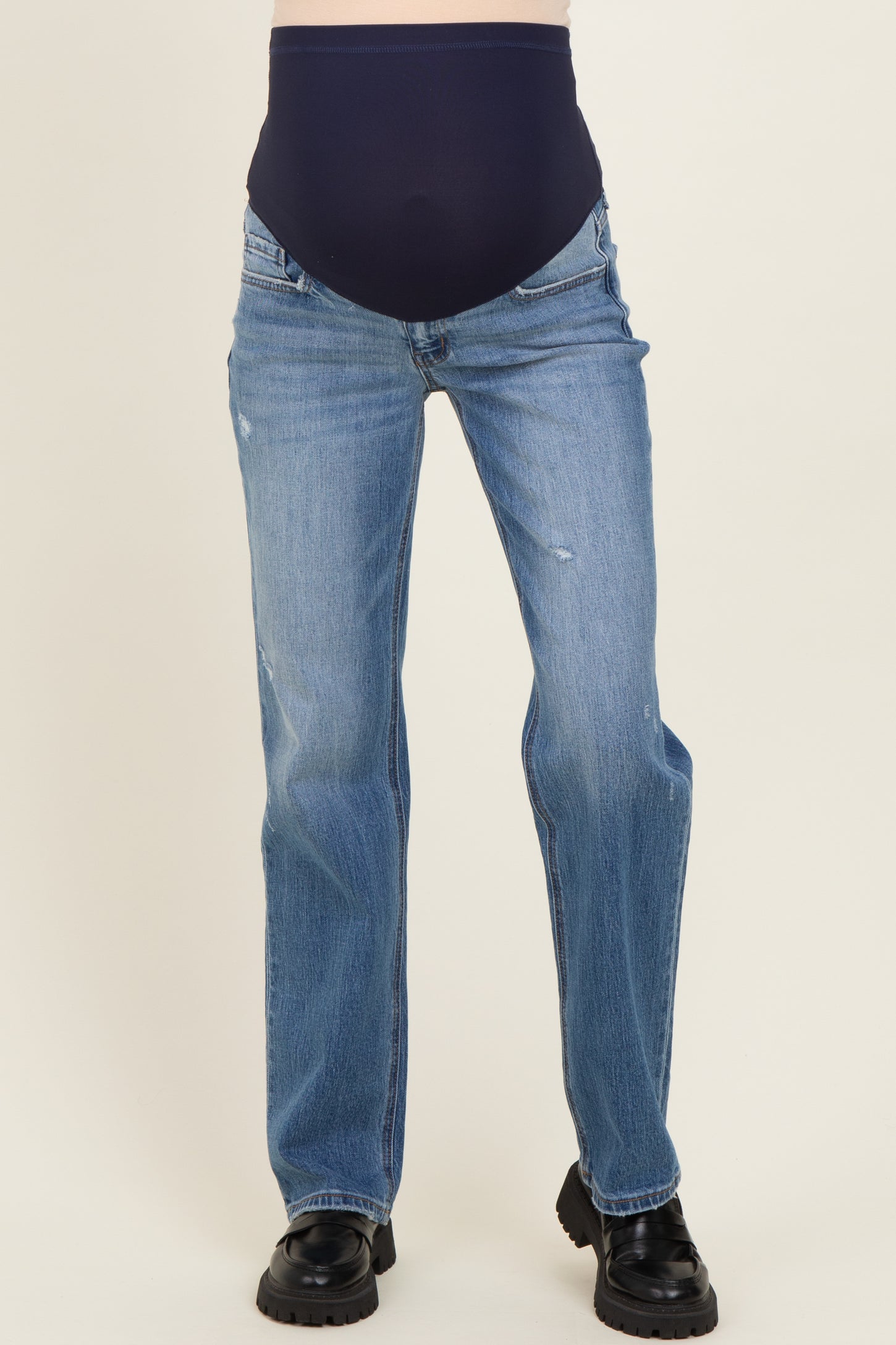 woman wearing a pair of light blue maternity jeans with a dark blue over-the-bump waistband and a slight distressed detail