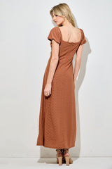 woman wearing a rust-colored maxi dress with puff sleeves and a back zip closure