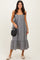 woman wearing a black and white gingham midi dress with buttons and a ruffle hem, holding a black woven bag