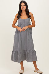 woman wearing a black and white gingham maxi dress with buttons and a ruffled hem, standing on a neutral background