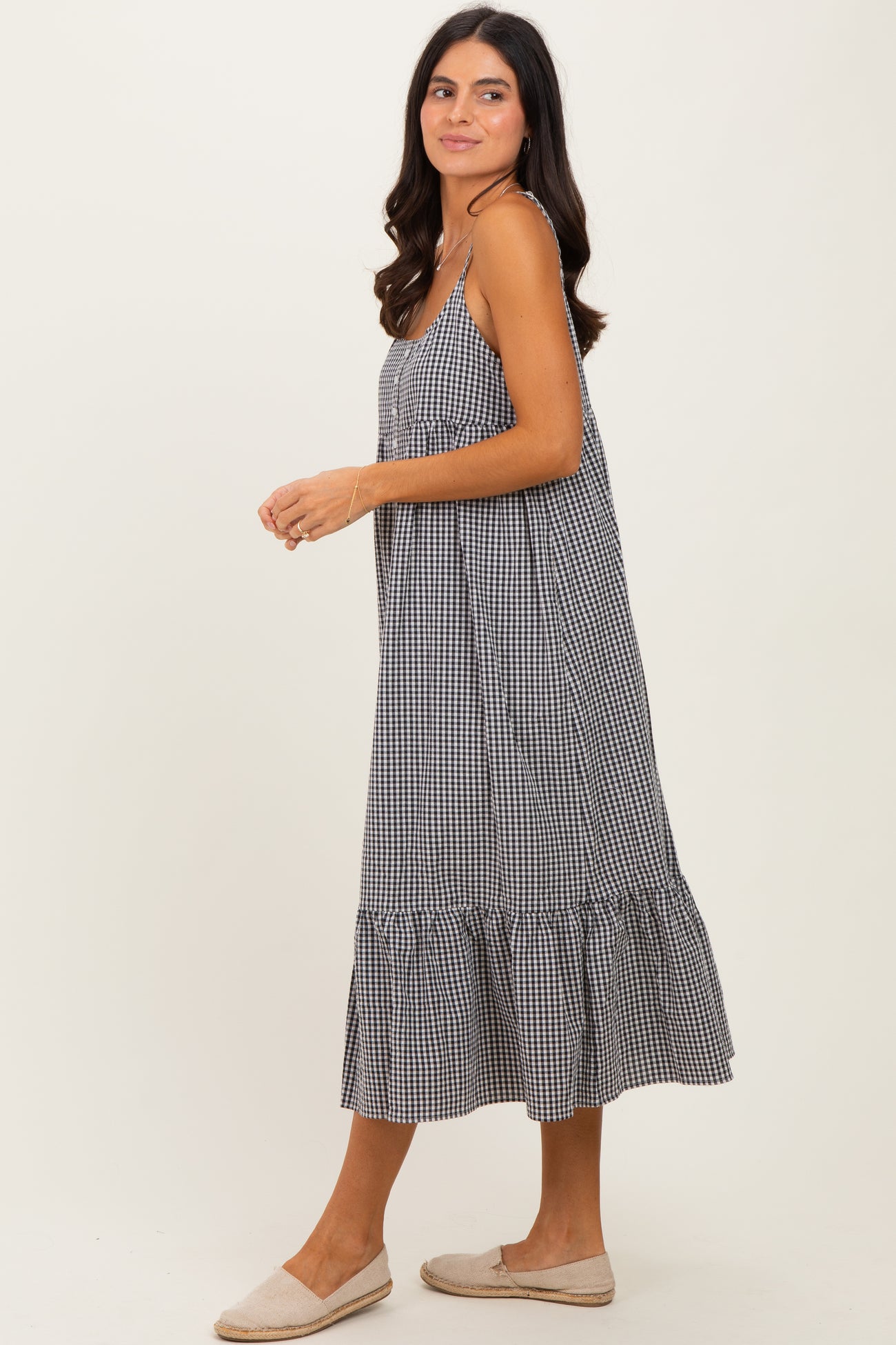 woman wearing a black and white gingham midi dress with spaghetti straps and a ruffled hem