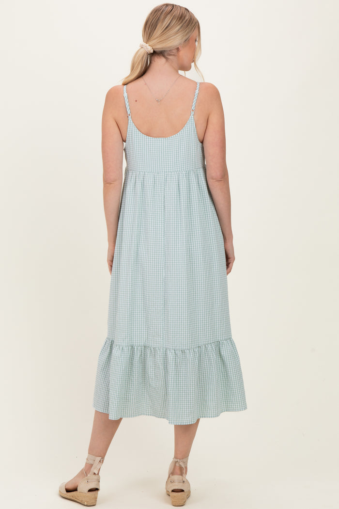 woman wearing a light green gingham midi dress with a tiered ruffle hem and adjustable straps, shown from the back