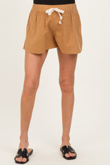 woman wearing tan maternity shorts with an elastic waistband and drawstring, paired with black slide sandals