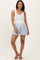 woman wearing a white tank top and light blue maternity shorts with drawstring detail