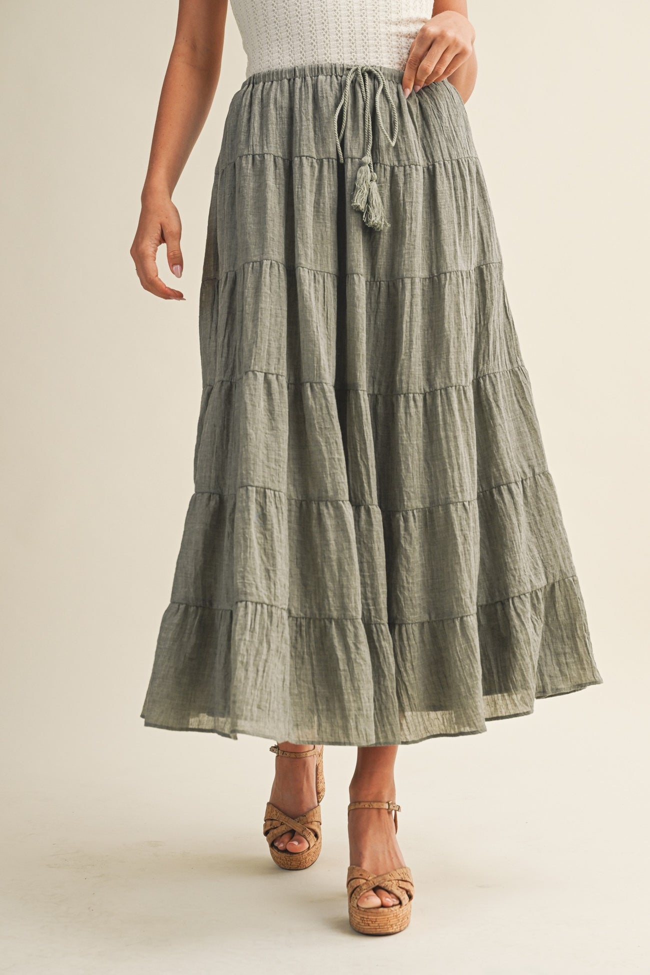 woman wearing a tiered olive green maxi skirt with a drawstring waist and tassel details