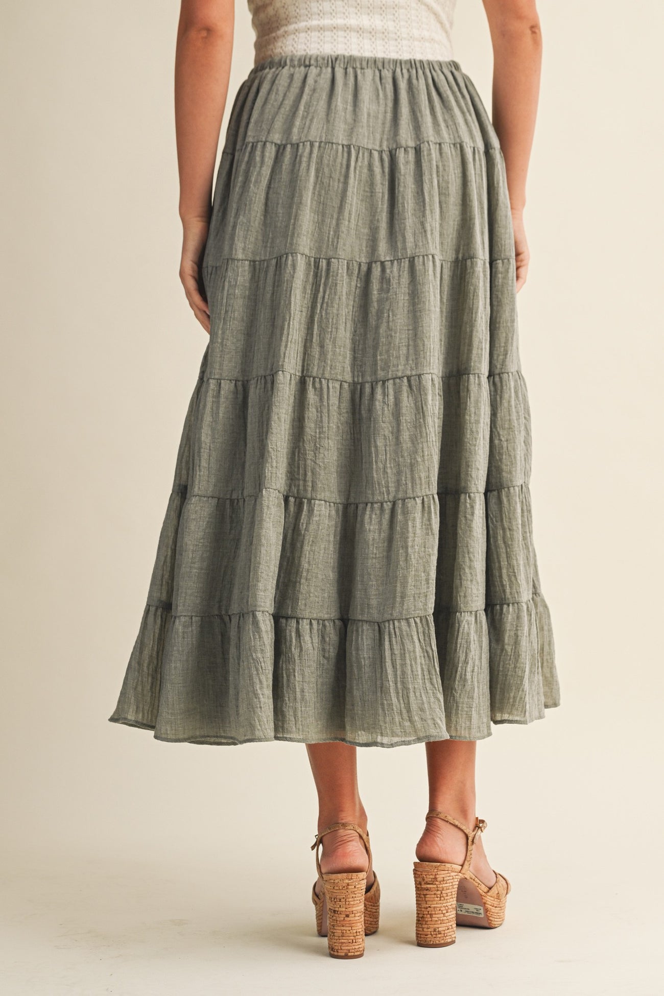 woman wearing a flowy olive green tiered maxi skirt with a comfortable waistband and styled with heeled sandals