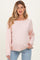 woman wearing a light pink oversized maternity sweater and showing her baby bump