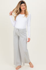 woman wearing a white long sleeve maternity top and grey striped wide-leg maternity pants with a drawstring waist
