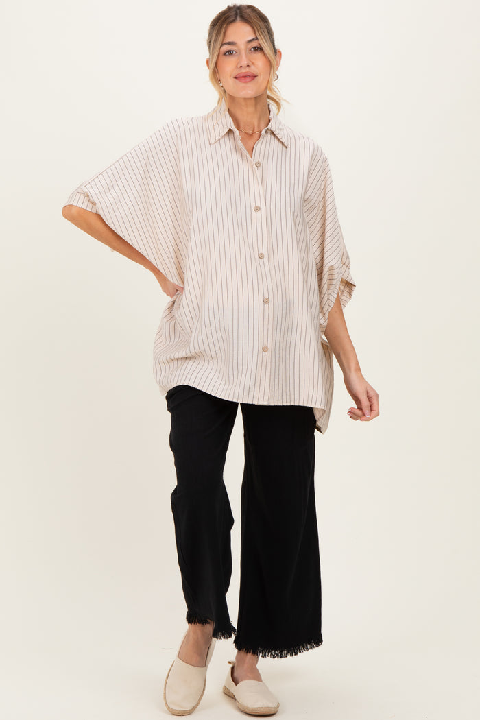 woman wearing a striped oversized button-up maternity shirt and black wide-leg pants, showing her baby bump