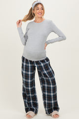 woman wearing a gray long sleeve maternity top and navy plaid maternity pants, showing her baby bump