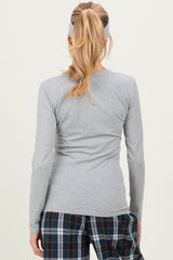 woman wearing a gray long sleeve maternity top, seen from the back, paired with plaid pajamas