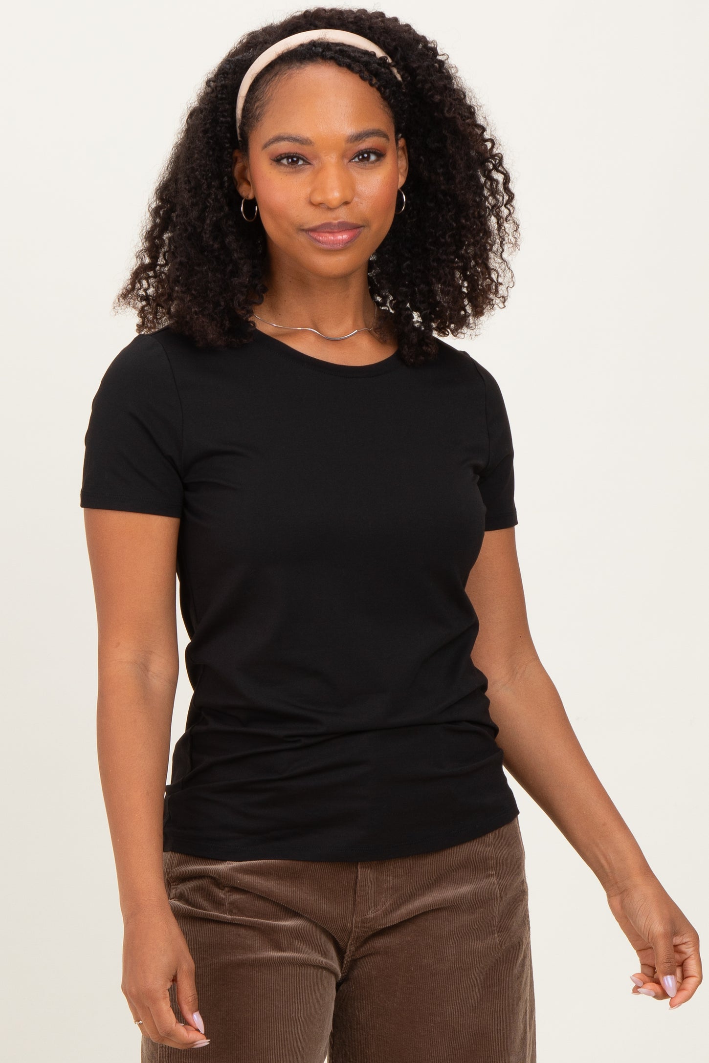 woman wearing a black short sleeve t-shirt with a fitted style and curly hair styled with a headband