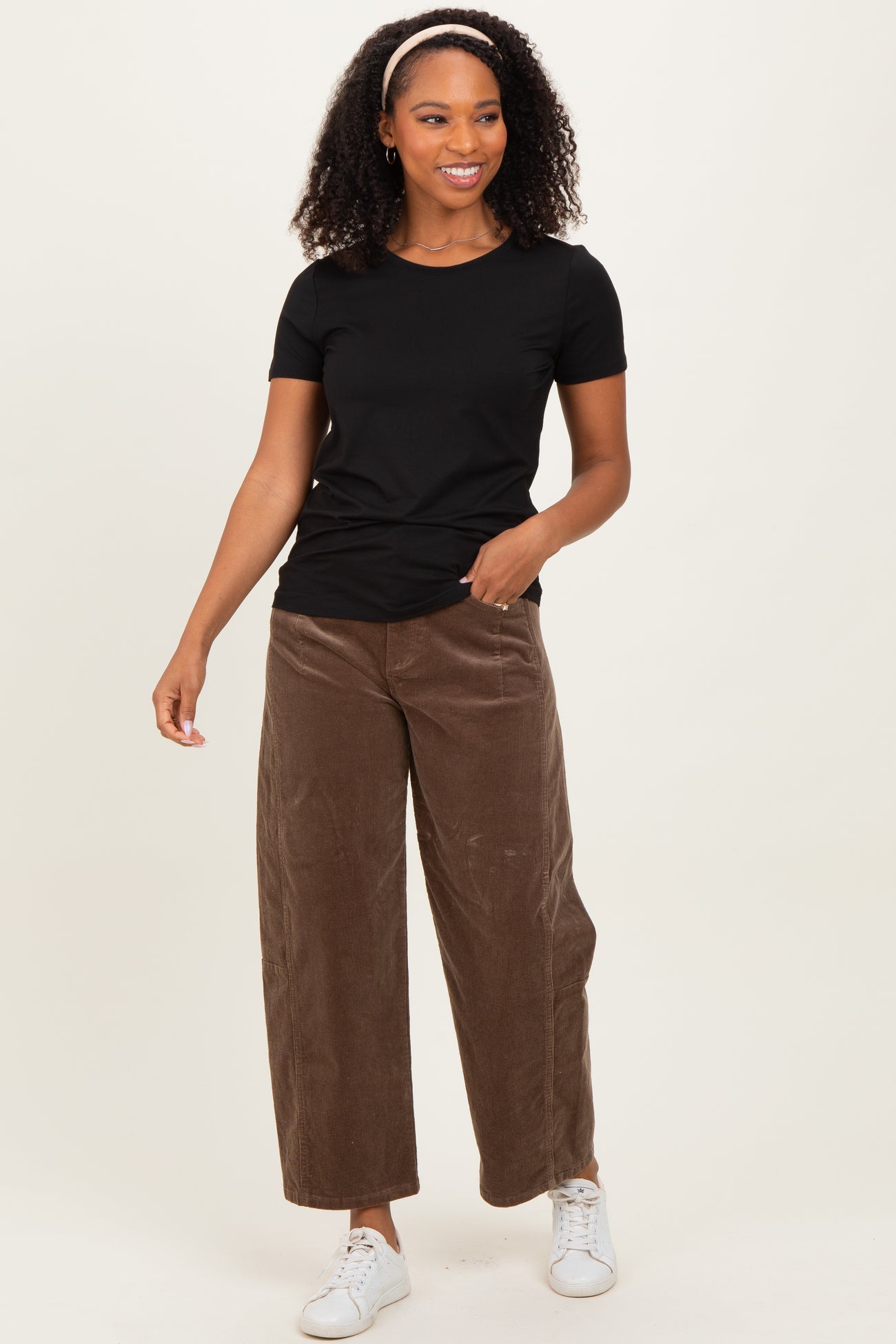 woman wearing a black short sleeve t-shirt and brown wide-leg corduroy pants with white sneakers