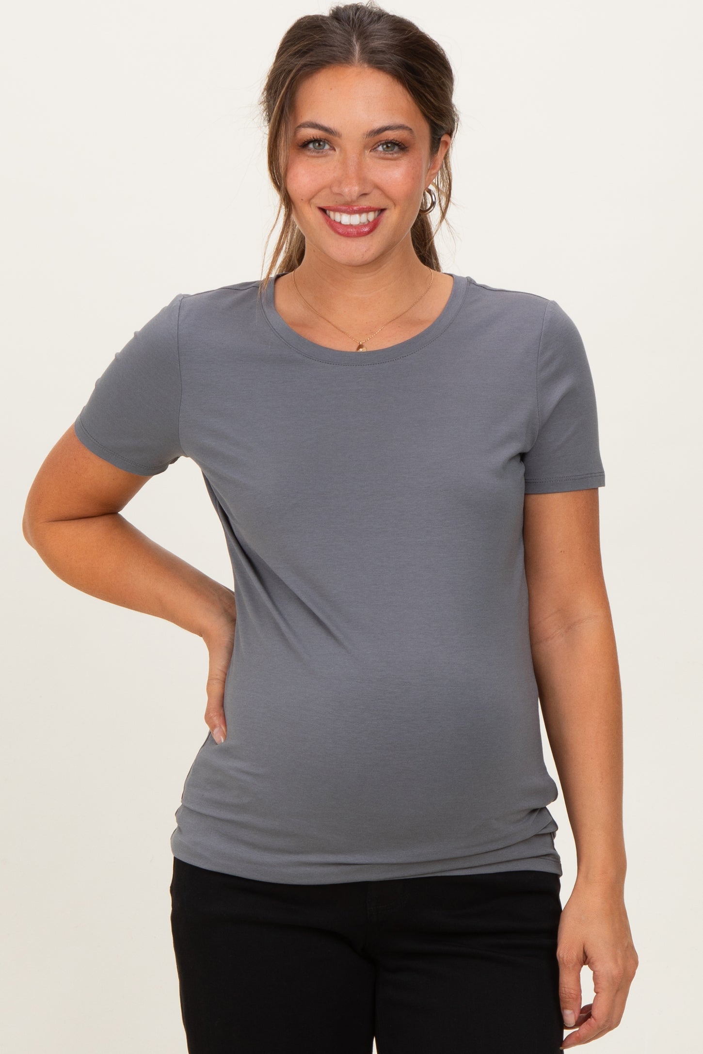 woman wearing a gray short sleeve maternity top and holding her baby bump