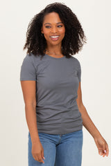 woman wearing a gray short sleeve t-shirt and blue jeans, smiling with curly hair