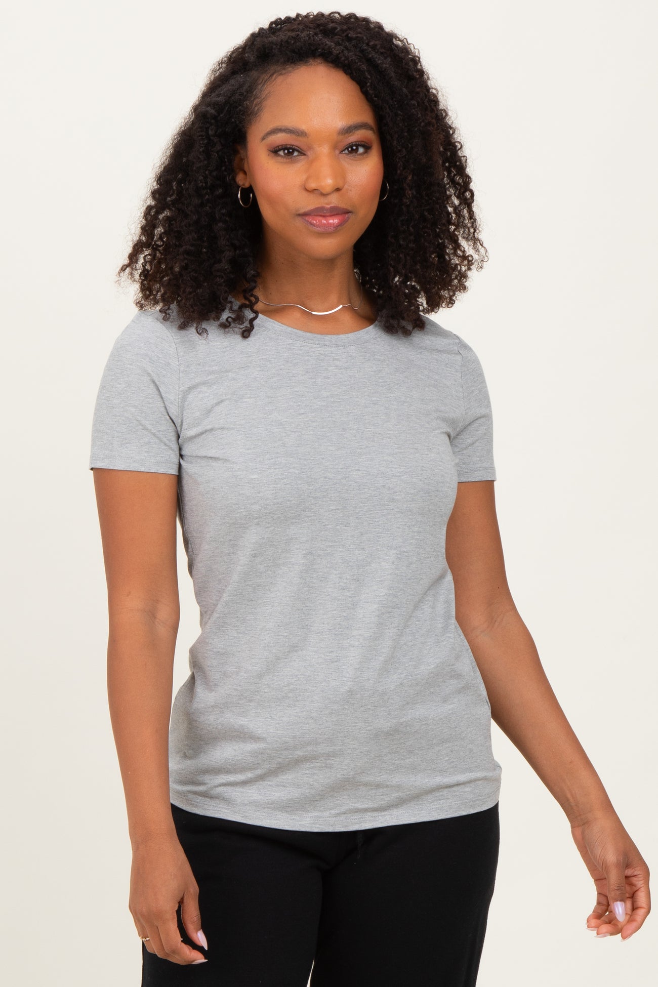 woman wearing a gray short sleeve t-shirt and black pants, standing in a neutral pose