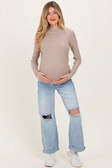 woman wearing a striped long sleeve maternity top and distressed light blue jeans, holding her baby bump