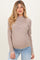 woman wearing a striped beige maternity top with a high neck and visible baby bump, paired with light blue jeans