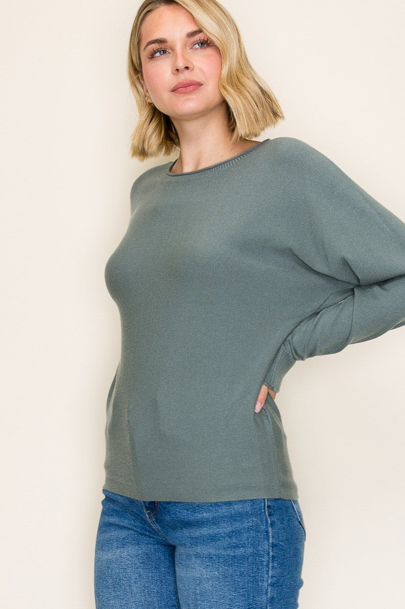woman wearing a green oversized long sleeve sweater with side pockets and styled with blue jeans