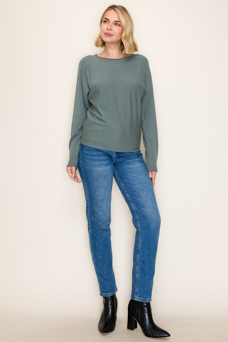 woman wearing a soft green long sleeve top and blue skinny jeans, paired with black ankle boots