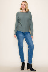 woman wearing a soft green long sleeve top and blue skinny jeans, paired with black ankle boots