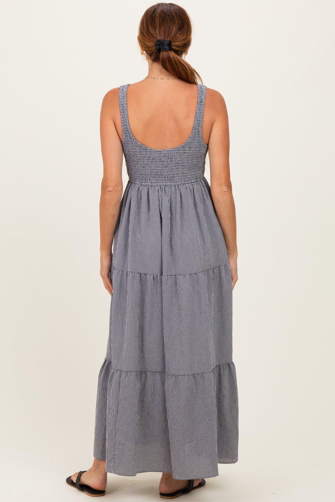 woman wearing a back view of a striped maxi dress with adjustable straps and tiered design