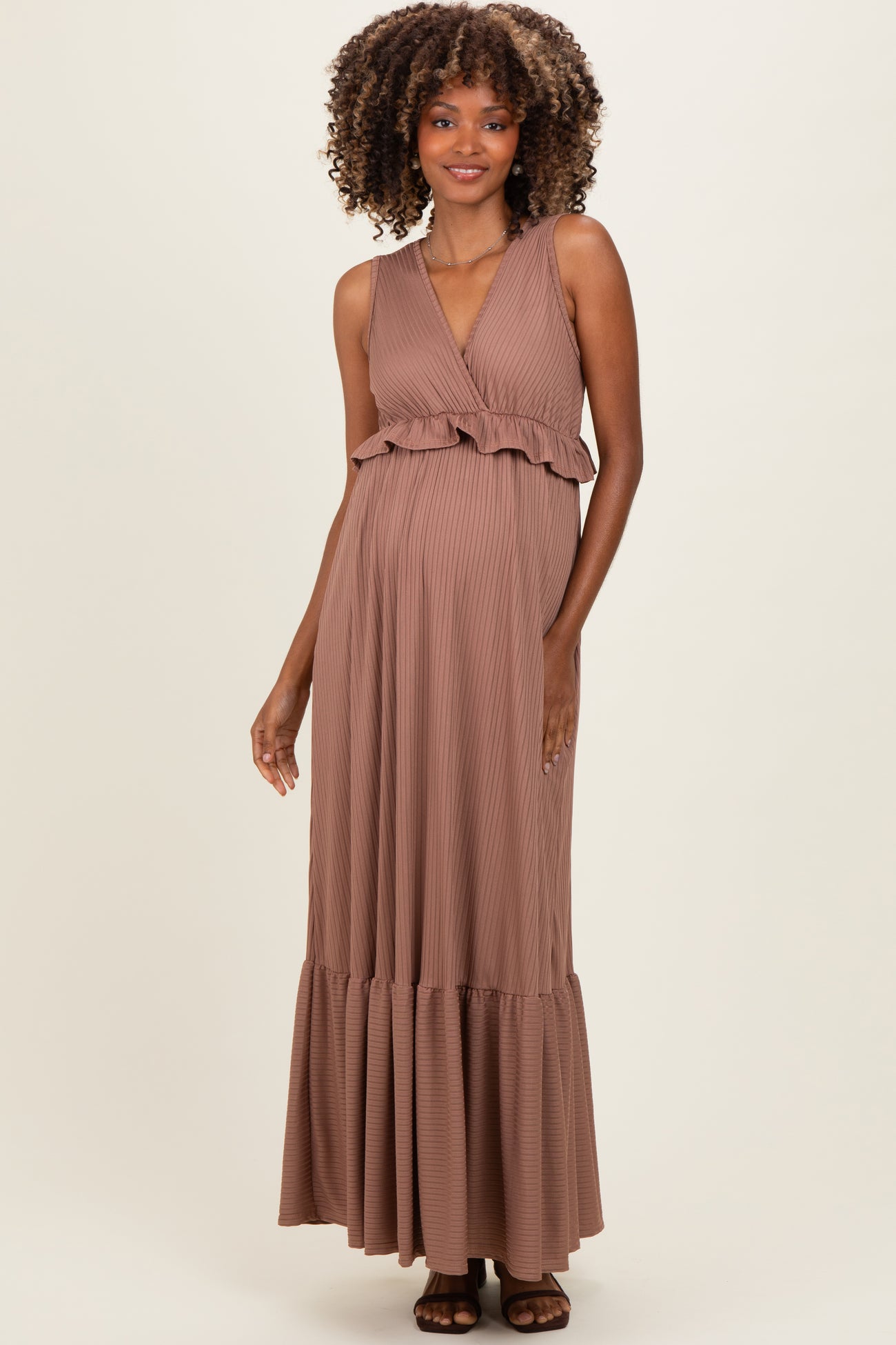 woman wearing a brown maternity maxi dress with ruffles and a flowing skirt, showing her baby bump