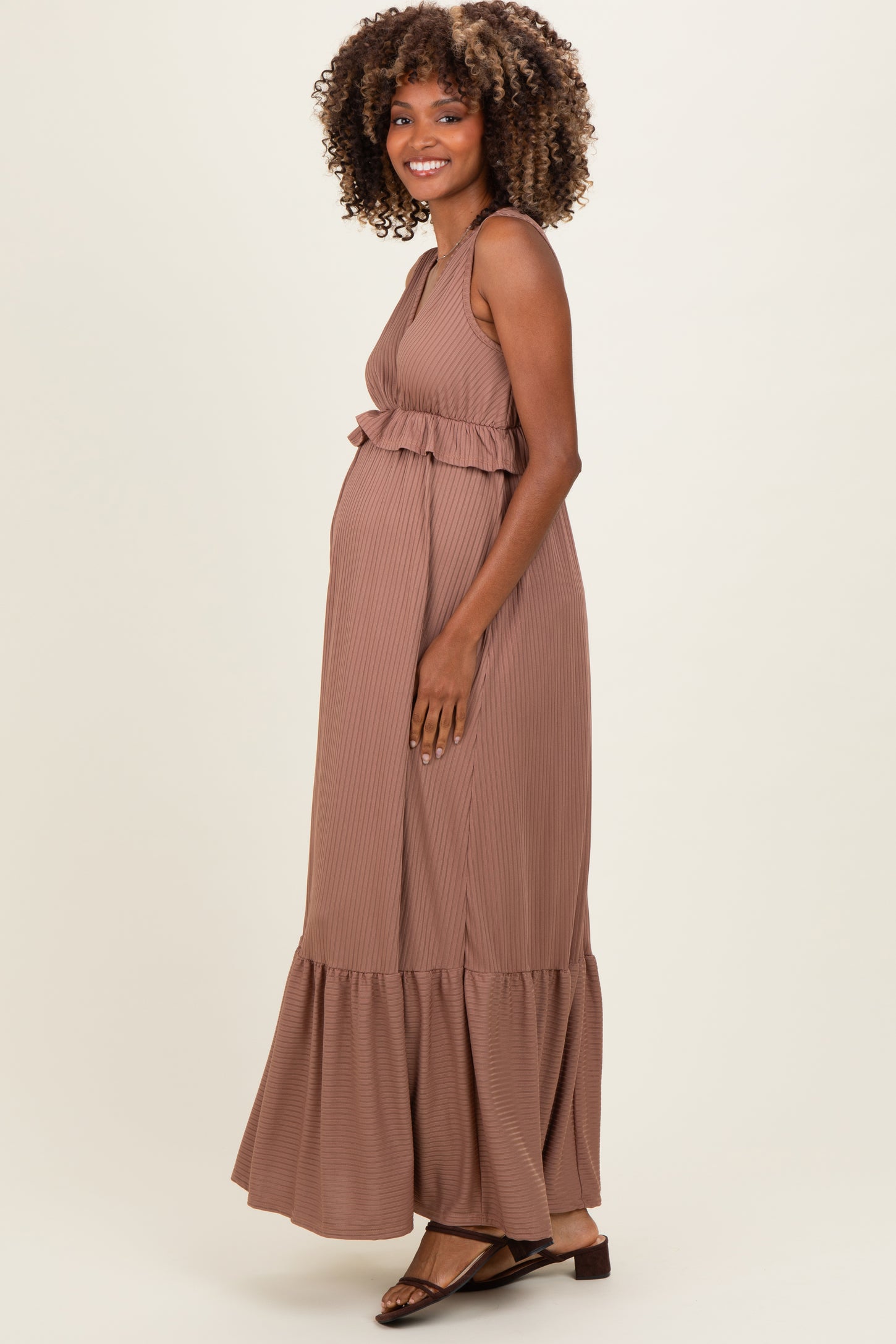 woman wearing a brown striped maternity maxi dress with a ruffle waist and a visible baby bump