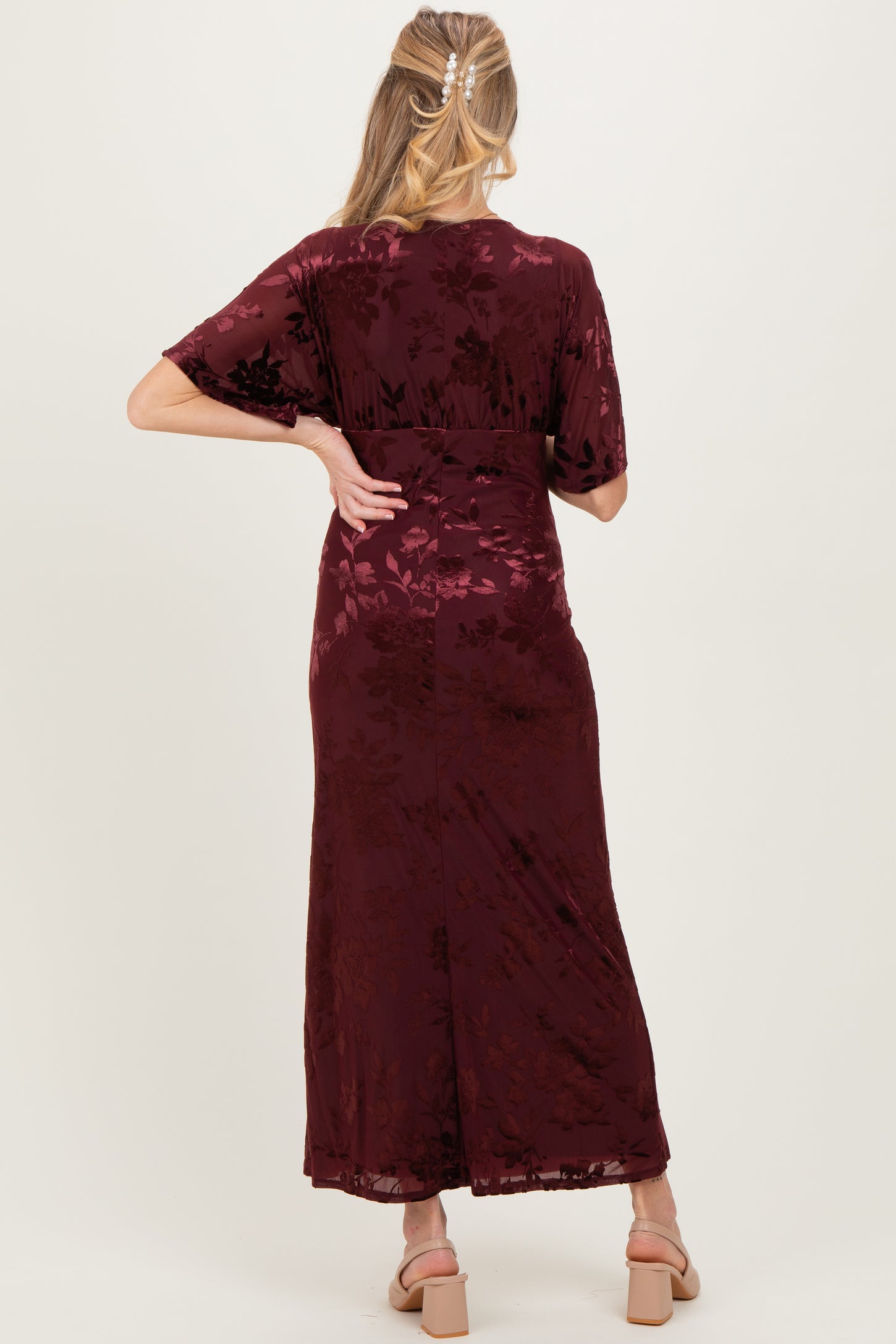 woman wearing a burgundy floral print maternity maxi dress, showing the back view with flowy sleeves