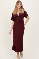 woman wearing a burgundy velvet maxi dress with a v-neckline and short sleeves