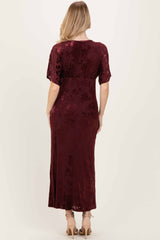 woman wearing a burgundy velvet maxi dress with short sleeves and floral patterns from the back view