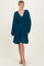 woman wearing a teal smocked waist long sleeve dress with a flared skirt and v-neckline